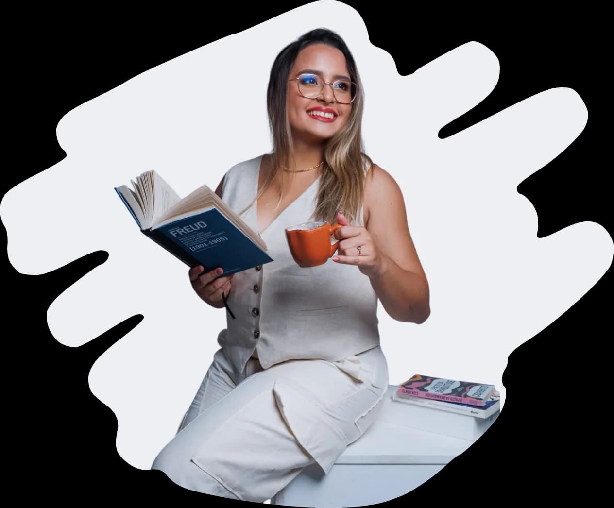 Evelin Paixão sentada, segurando um livro e uma xícara.