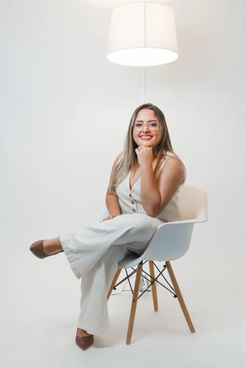 Evelin Paixão sentada em uma poltrona, sorrindo.